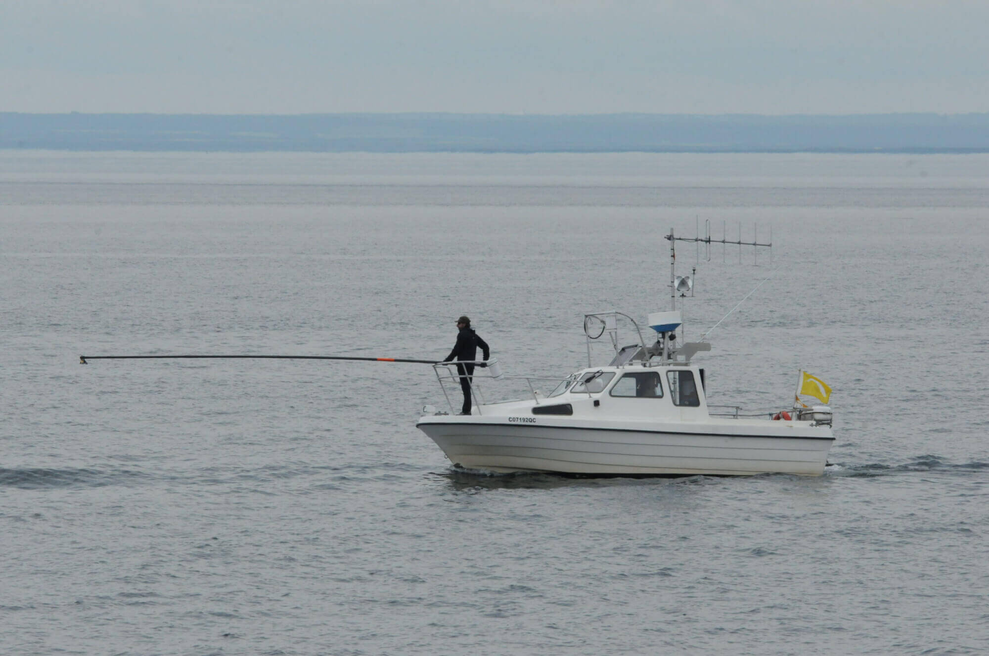 The chief technician equipped with a pole to place a transmitter on a cetacean.